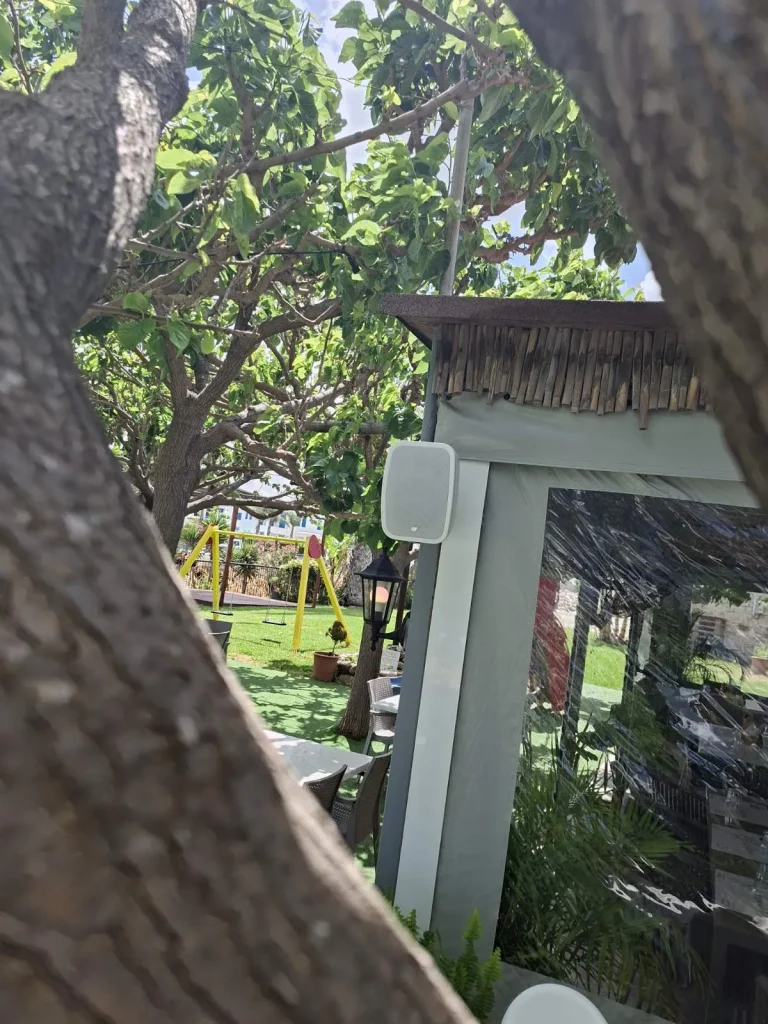Outdoor speaker mounted on a wooden pergola at S.K. Yiallos Beach Kebab